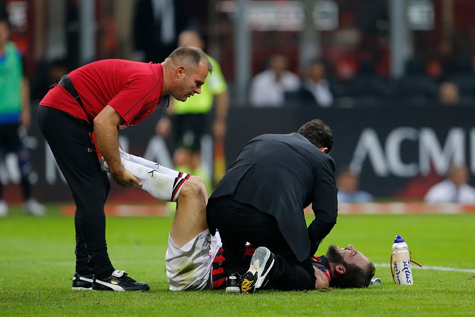 Emergency medical personnel assessing a football player after collapsing during a football match